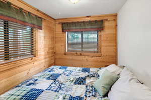 Bedroom featuring wooden walls and multiple windows