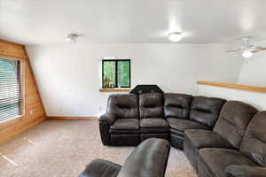 Carpeted living room featuring baseboards and ceiling fan