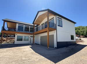 Back of property with a garage, a balcony, and driveway