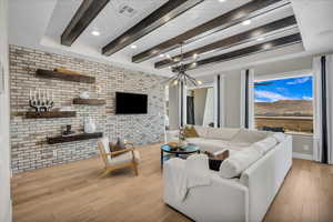 Living room with brick wall, light wood-type flooring, a chandelier, beamed ceiling, and recessed lighting