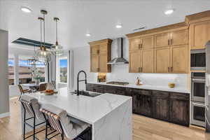 Kitchen featuring light wood finished floors, recessed lighting, backsplash, light stone counters, and appliances with stainless steel finishes