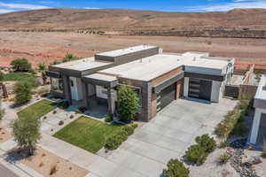 View of front of property featuring concrete driveway, a mountain view, view of desert, a garage, and a gate