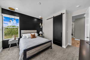 Bedroom with a barn door, a textured ceiling, light carpet, wooden walls, and recessed lighting