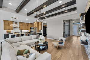 Living room with a chandelier, light wood-type flooring, beam ceiling, and recessed lighting
