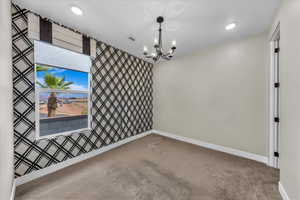 Carpeted empty room with baseboards and a chandelier