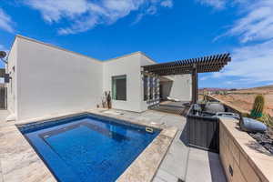 Rear view of property with stucco siding, area for grilling, a patio, and an outdoor pool