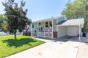 Raised ranch featuring concrete driveway, a carport, brick siding, a shingled roof, and covered porch