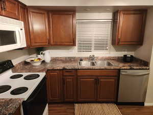 Kitchen with electric range, stainless steel dishwasher, white microwave, and dark wood-type flooring