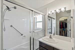 Full bathroom with an enclosed shower, a walk in closet, and vanity
