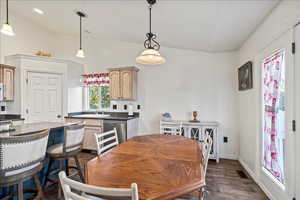 Dining area with vaulted ceiling and dark wood-style floors