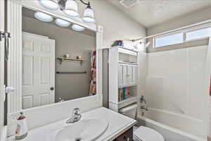 Full bathroom with vanity, shower / bath combination with curtain, and a textured ceiling