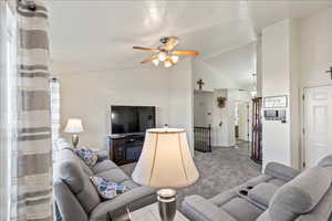 Carpeted living room featuring a ceiling fan and high vaulted ceiling