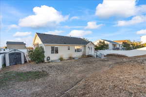 Rear view of property with a storage unit and a shingled roof