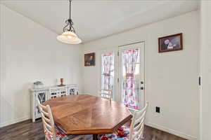 Dining area with dark wood-style floors and vaulted ceiling
