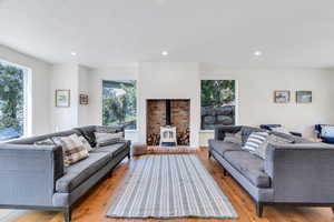 Living room with a wood stove, light wood-type flooring, and recessed lighting