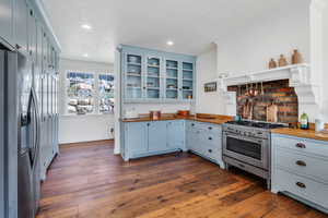 Kitchen with wooden counters, stainless steel appliances, open shelves, blue cabinets, and crown molding