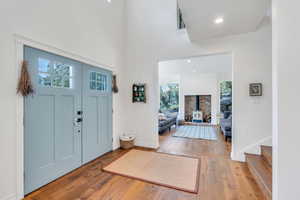 Entryway featuring hardwood / wood-style flooring, a wood stove, recessed lighting, and a towering ceiling