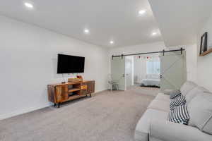 Living room featuring light colored carpet, recessed lighting, and a barn door