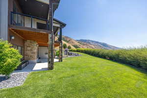 View of grassy yard featuring a mountain view, a patio area, and a balcony