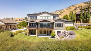 Back of house featuring a patio area, a mountain view, stone siding, and a standing seam roof