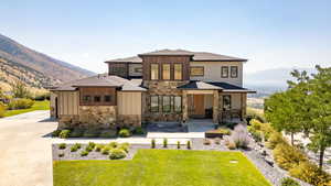 View of front of property featuring stone siding, board and batten siding, a mountain view, and a front yard