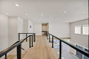 Corridor featuring light wood finished floors, an upstairs landing, and recessed lighting