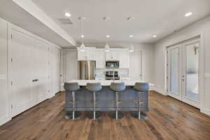 Kitchen featuring white cabinetry, a center island with sink, appliances with stainless steel finishes, recessed lighting, and dark wood-type flooring