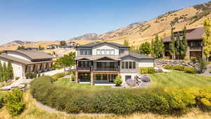 Back of property featuring a mountain view, a balcony, a patio, and stone siding