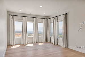 Empty room with light wood-style flooring, healthy amount of natural light, and recessed lighting