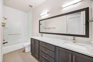 Bathroom with double vanity, washtub / shower combination, and tile patterned floors