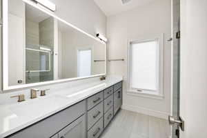 Full bath with double vanity, a stall shower, and tile patterned floors