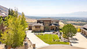 View of front of home featuring stone siding, curved driveway, a mountain view, board and batten siding, and a front yard
