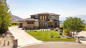 View of front facade with board and batten siding, a mountain view, concrete driveway, stone siding, and a garage