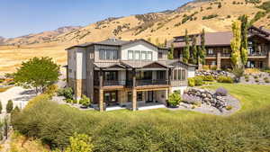 Rear view of house with stone siding, a standing seam roof, a patio area, a metal roof, and a mountain view
