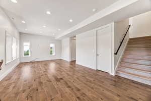 Unfurnished living room with stairway, wood finished floors, and recessed lighting