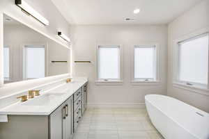 Full bath featuring double vanity, a freestanding tub, recessed lighting, and tile patterned flooring