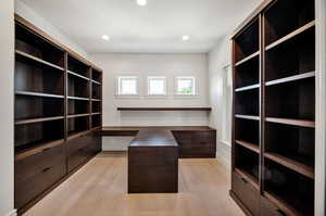 Walk in closet featuring light wood-style floors and built in study area