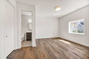 Unfurnished bedroom with dark wood-style floors and ensuite bathroom