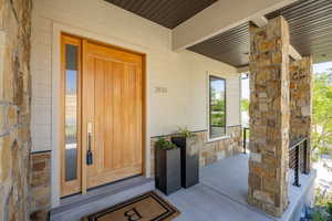 Property entrance featuring covered porch and stone siding