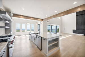 Kitchen featuring open shelves, stainless steel appliances, open floor plan, light wood-style flooring, and recessed lighting