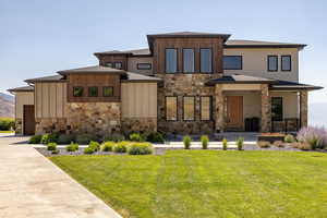 Prairie-style house featuring stone siding, covered porch, and a front lawn