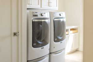 Washroom featuring washer and clothes dryer and cabinet space