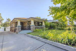 View of front of property with a porch, an outdoor structure, a front lawn, a garage, and stone siding