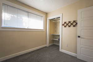 Unfurnished bedroom with baseboards and dark carpet