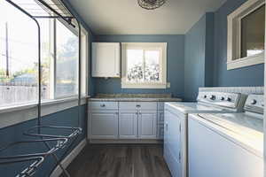 Laundry room featuring washer and clothes dryer, cabinet space, and dark wood finished floors