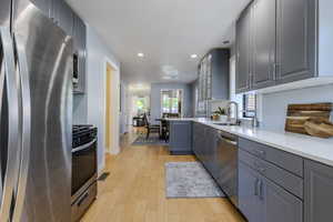 Kitchen featuring appliances with stainless steel finishes, gray cabinetry, recessed lighting, light wood finished floors, and light countertops