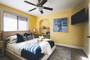 Carpeted bedroom featuring baseboards and ceiling fan