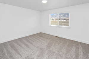 Carpeted spare room featuring baseboards