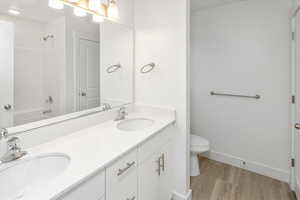 Full bathroom featuring double vanity, wood finished floors, and  shower combination