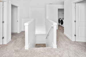 Hall with washing machine and clothes dryer, an upstairs landing, and carpet flooring